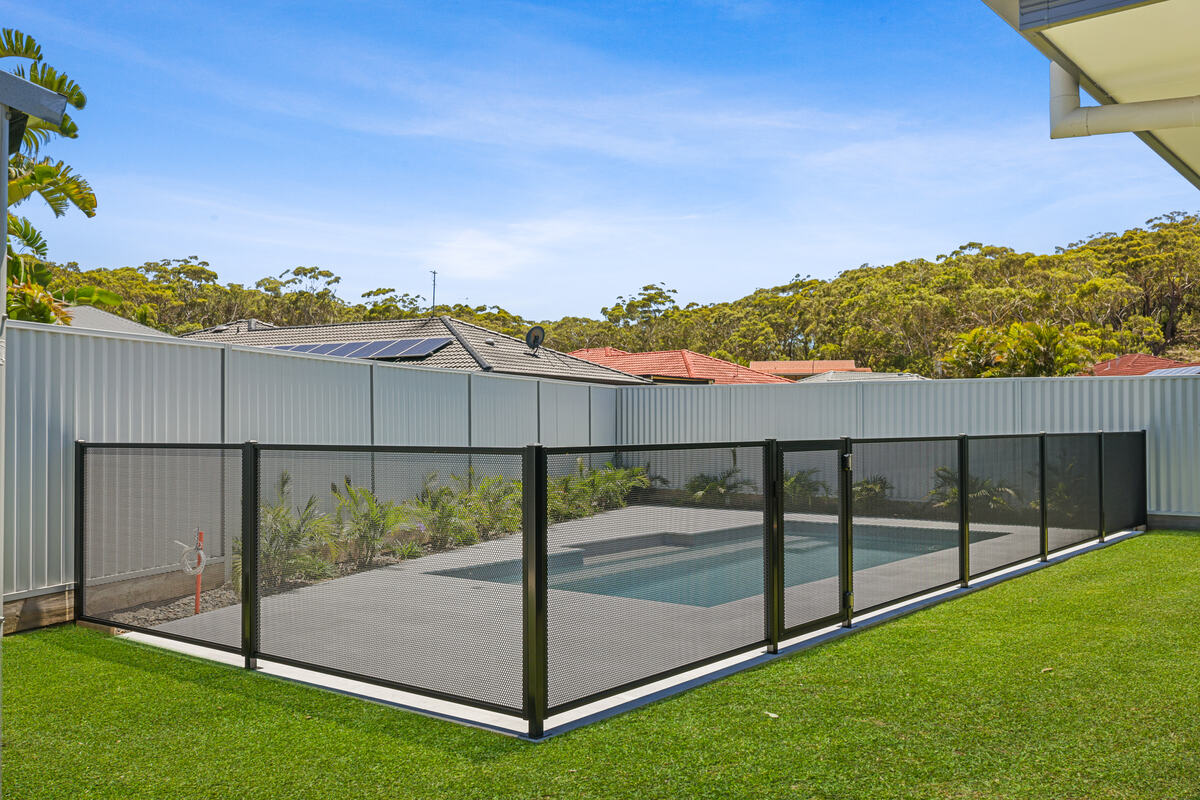 Pure Perf pool fence around a pool and travertine paving, NSW Mid North Coast