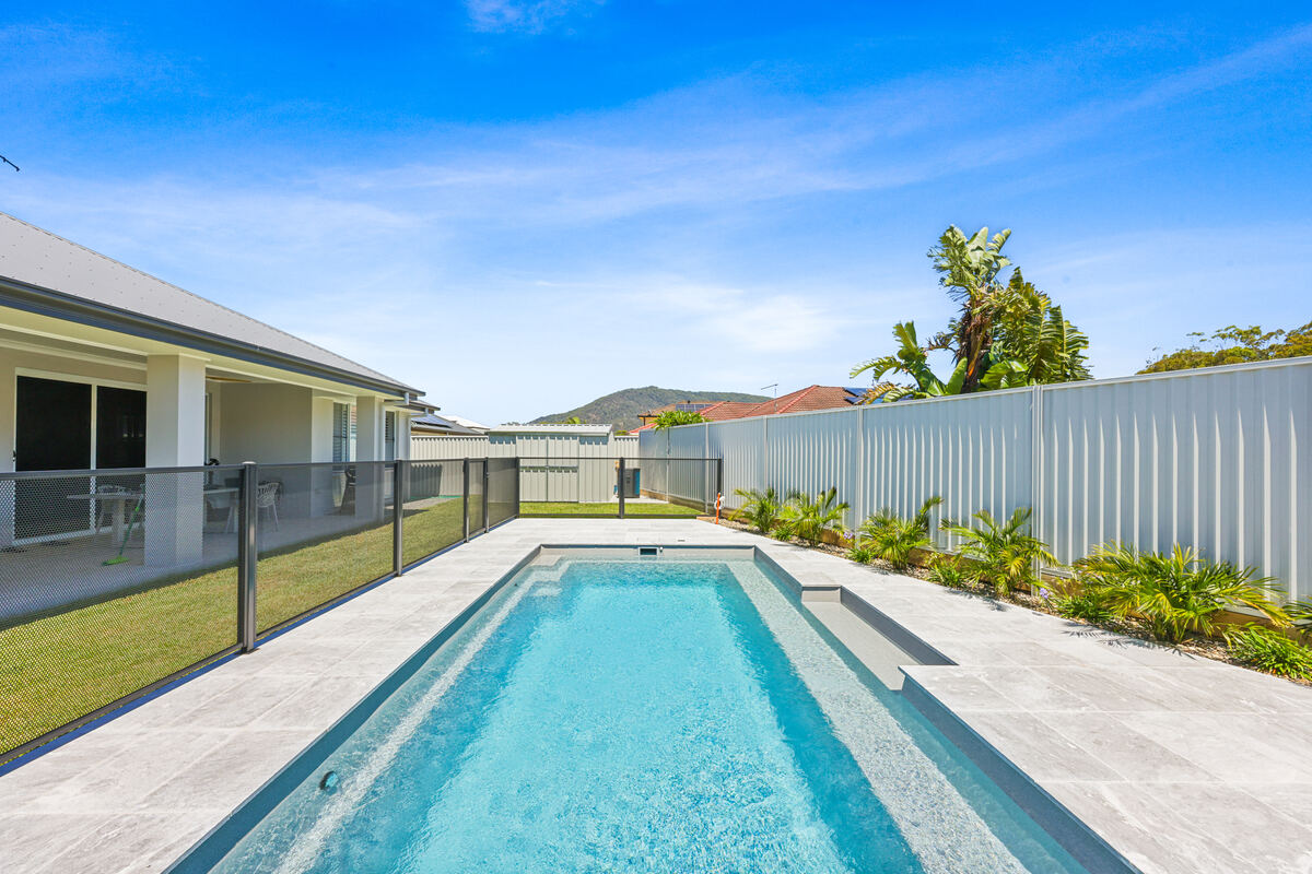 Pure Perf pool fencing in Textured Black along a long pool with travertine paving, Port Macquarie